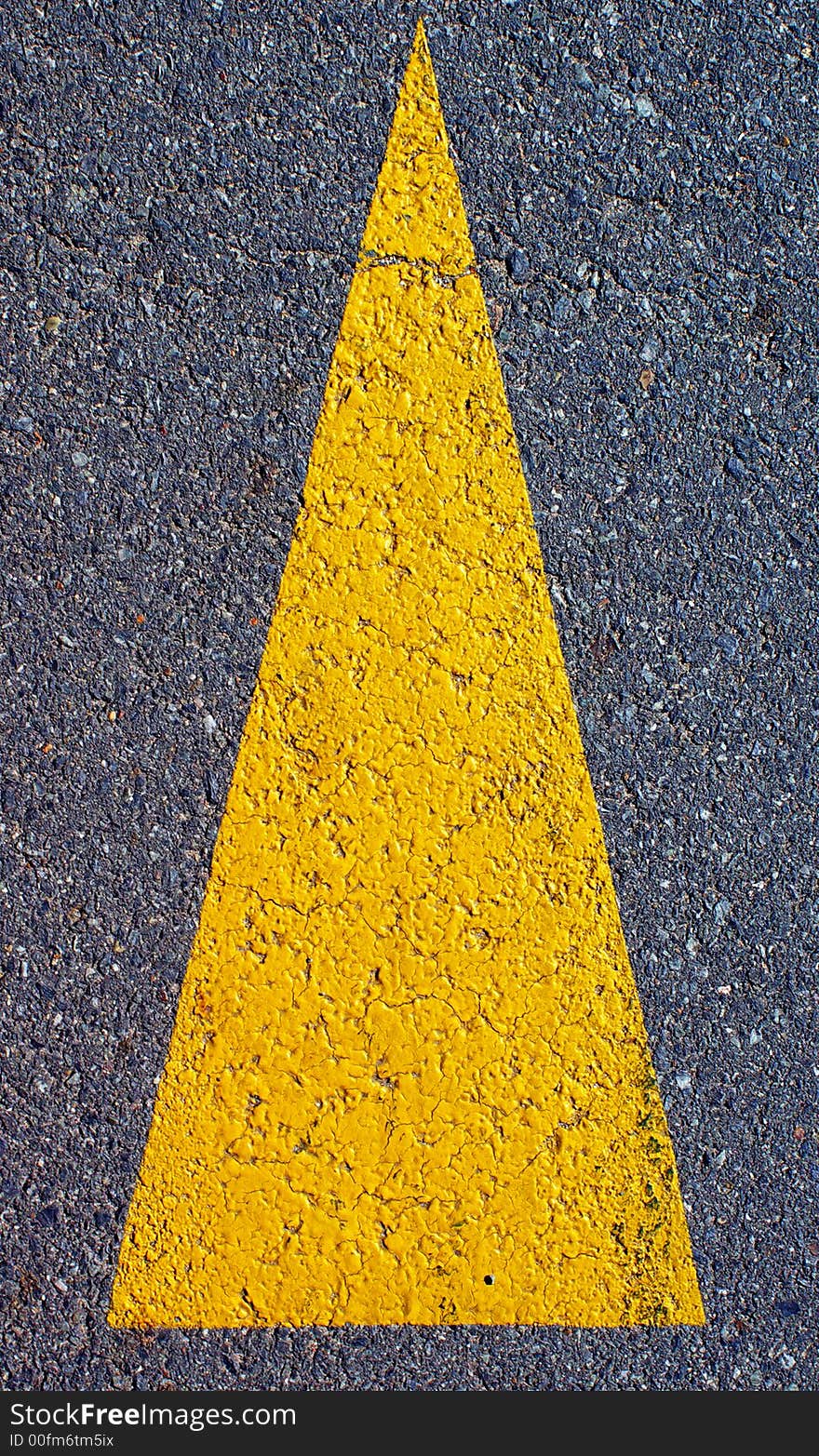 A yellow arrow symbol painted on a road. A yellow arrow symbol painted on a road