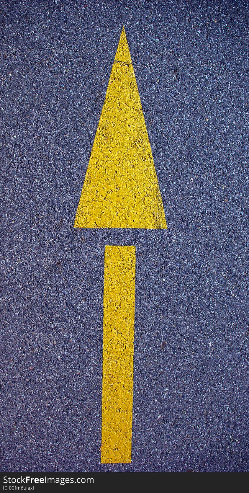 A yellow arrow symbol painted on a road. A yellow arrow symbol painted on a road