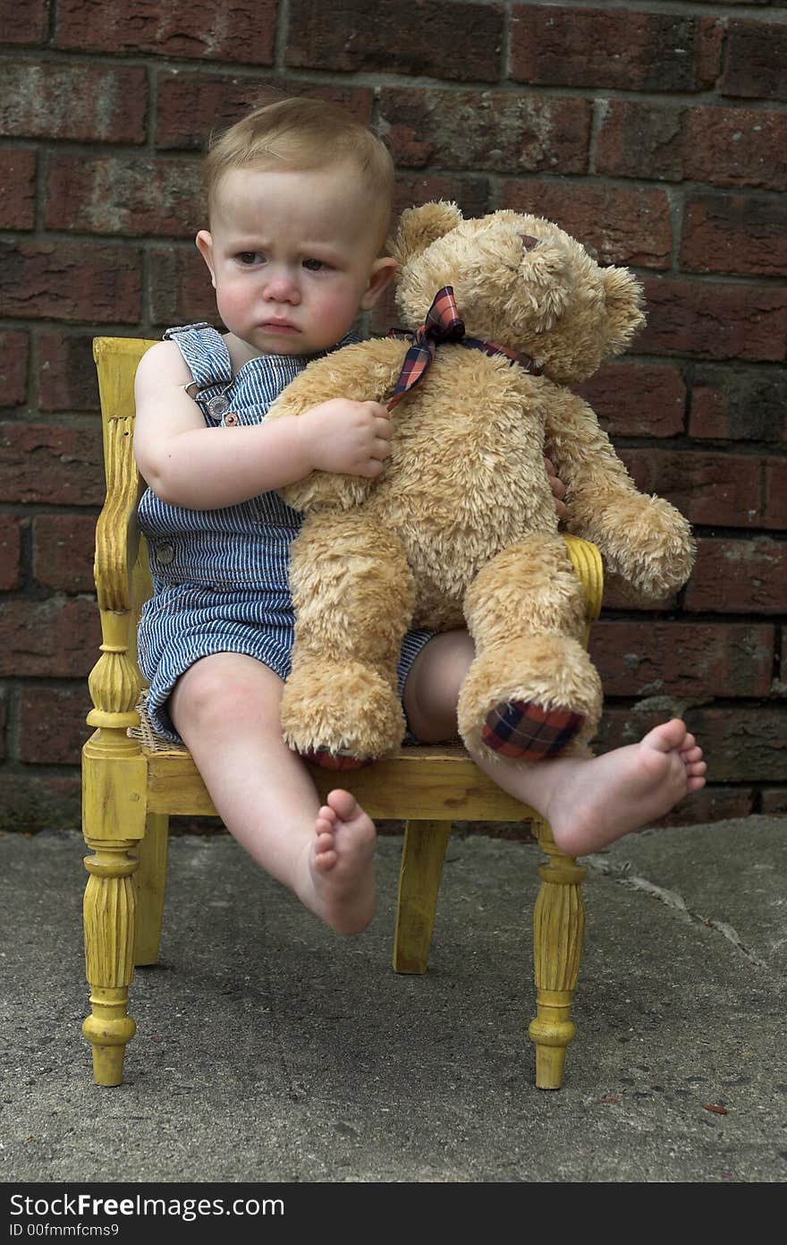 Image of cute toddler and teddy bear sitting in a chair