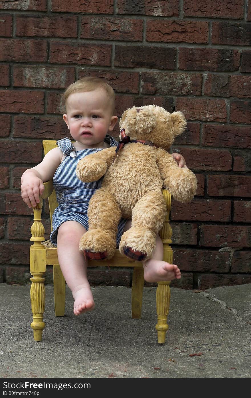 Image of cute toddler and teddy bear sitting in a chair