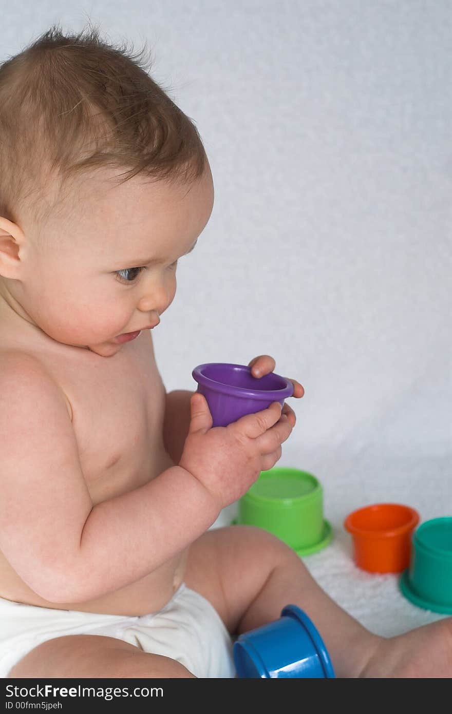 Image of an adorable baby playing with colorful stacking cups. Image of an adorable baby playing with colorful stacking cups