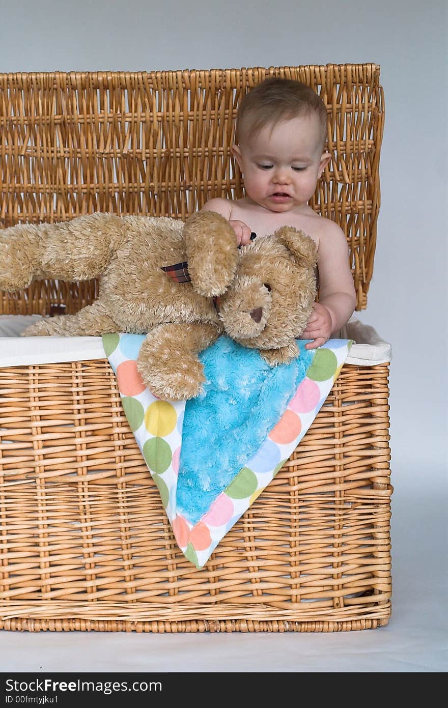 Image of cute baby and teddy bear peeking out of a wicker trunk