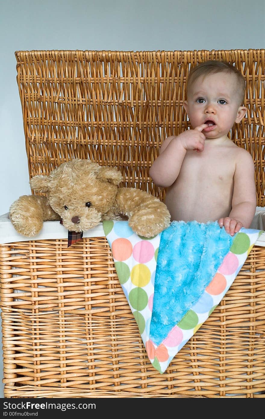 Image of cute baby and teddy bear peeking out of a wicker trunk