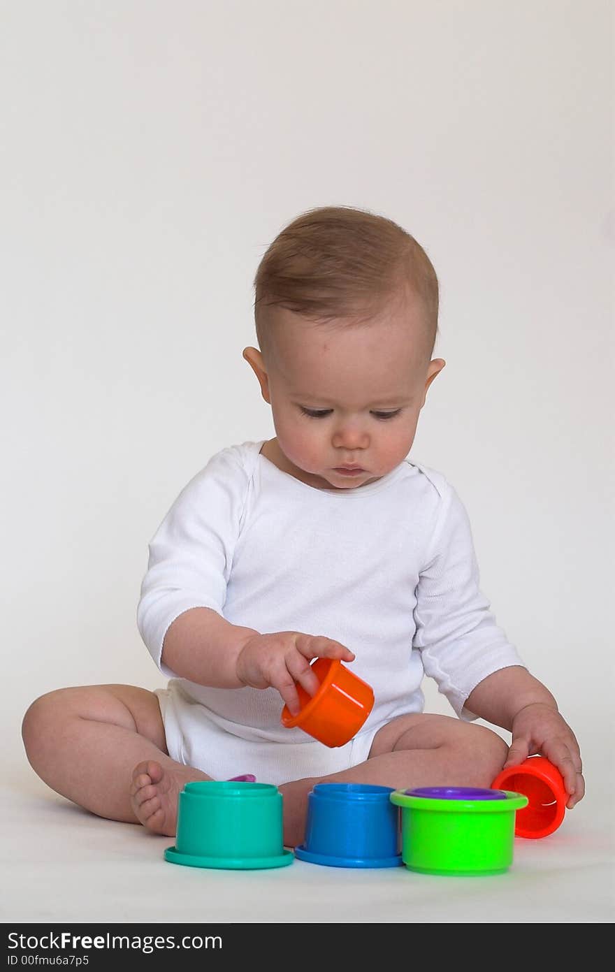 Image of an adorable baby playing with colorful stacking cups. Image of an adorable baby playing with colorful stacking cups