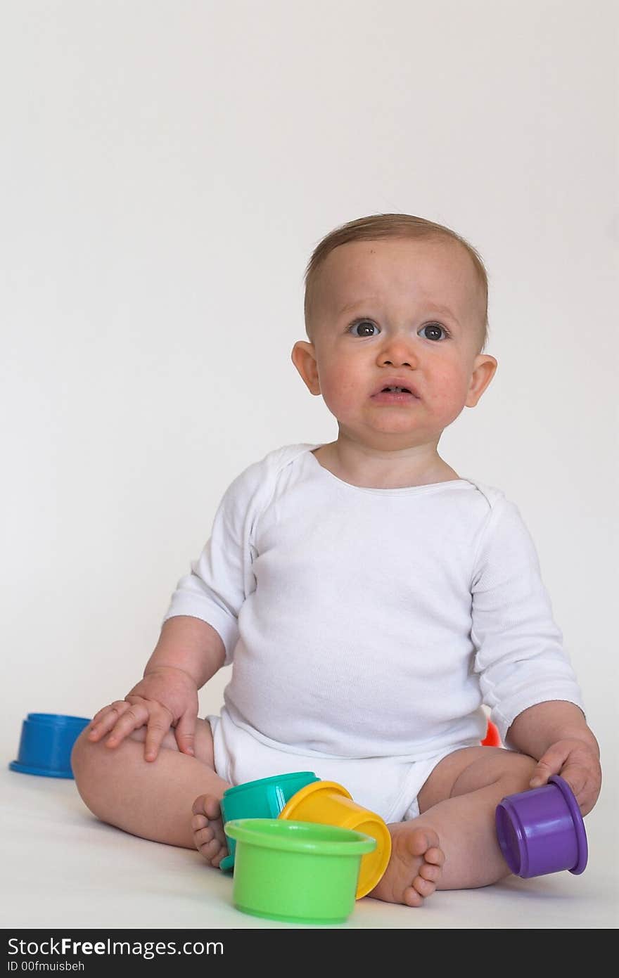 Image of an adorable baby playing with colorful stacking cups. Image of an adorable baby playing with colorful stacking cups