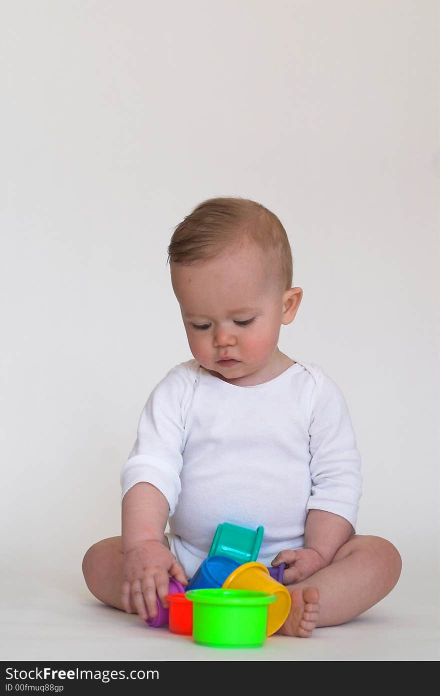 Image of an adorable baby playing with colorful stacking cups. Image of an adorable baby playing with colorful stacking cups