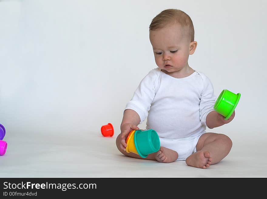 Image of an adorable baby playing with colorful stacking cups. Image of an adorable baby playing with colorful stacking cups