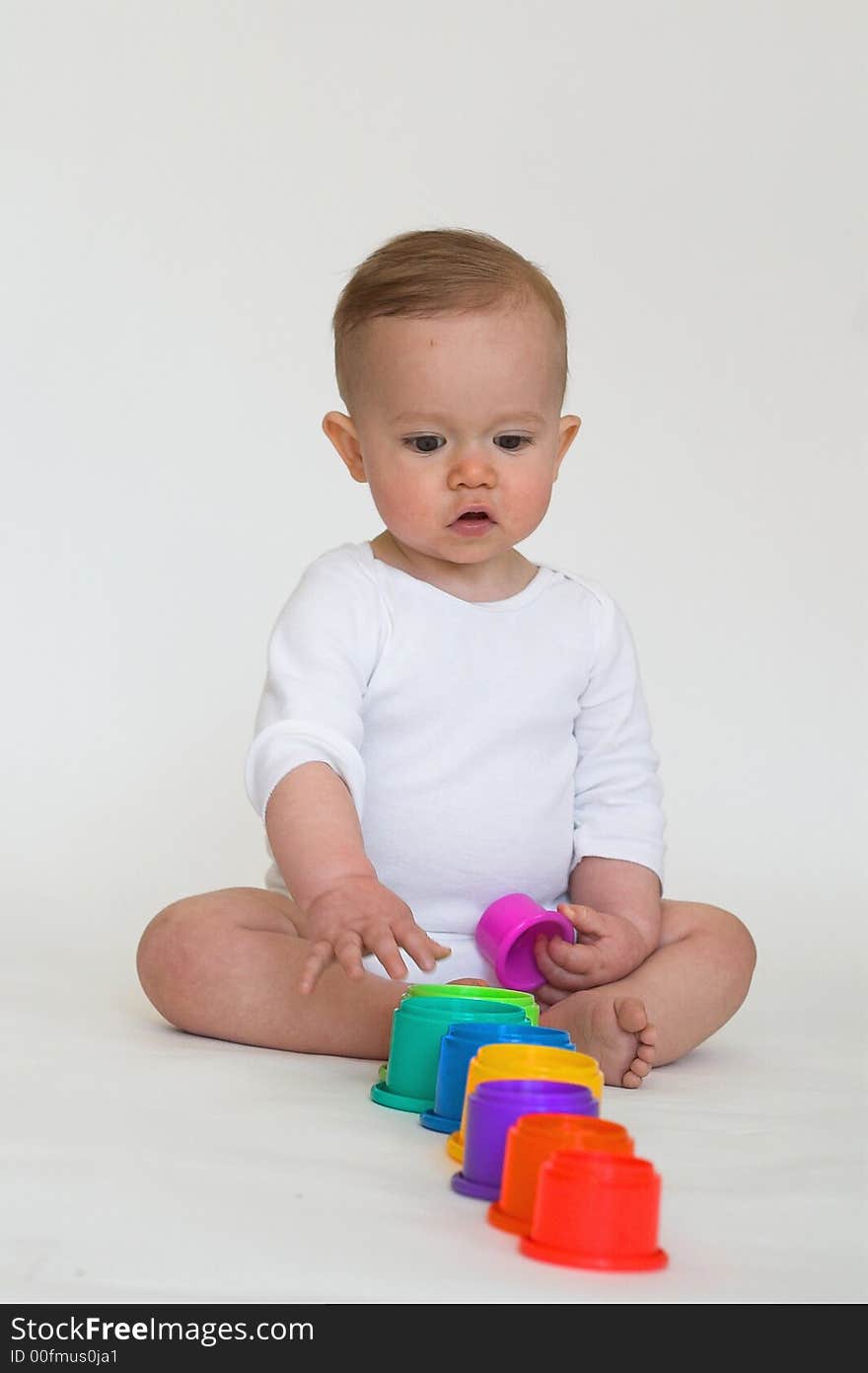 Image of an adorable baby playing with colorful stacking cups. Image of an adorable baby playing with colorful stacking cups