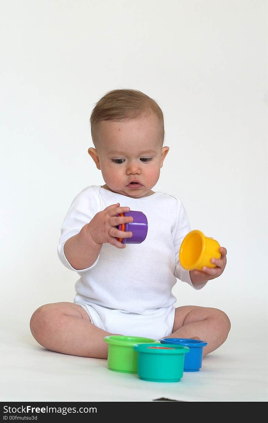 Image of an adorable baby playing with colorful stacking cups. Image of an adorable baby playing with colorful stacking cups