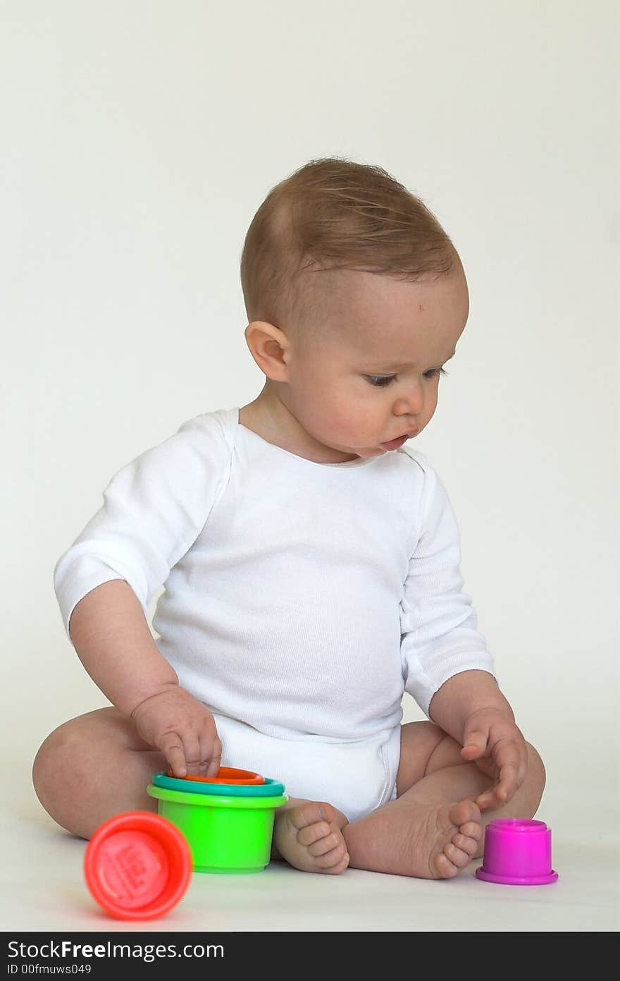 Image of an adorable baby playing with colorful stacking cups. Image of an adorable baby playing with colorful stacking cups