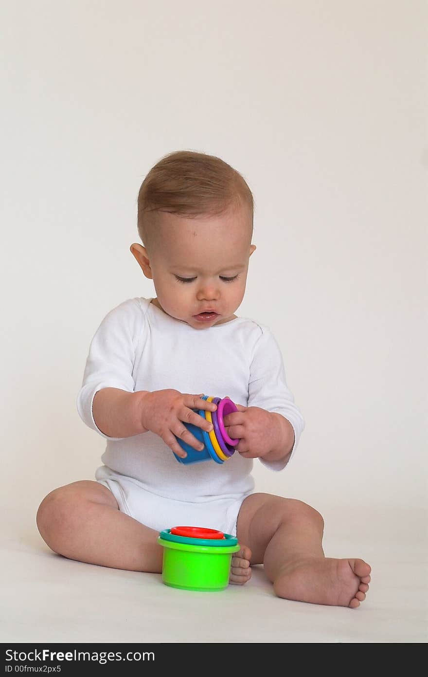 Image of an adorable baby playing with colorful stacking cups. Image of an adorable baby playing with colorful stacking cups