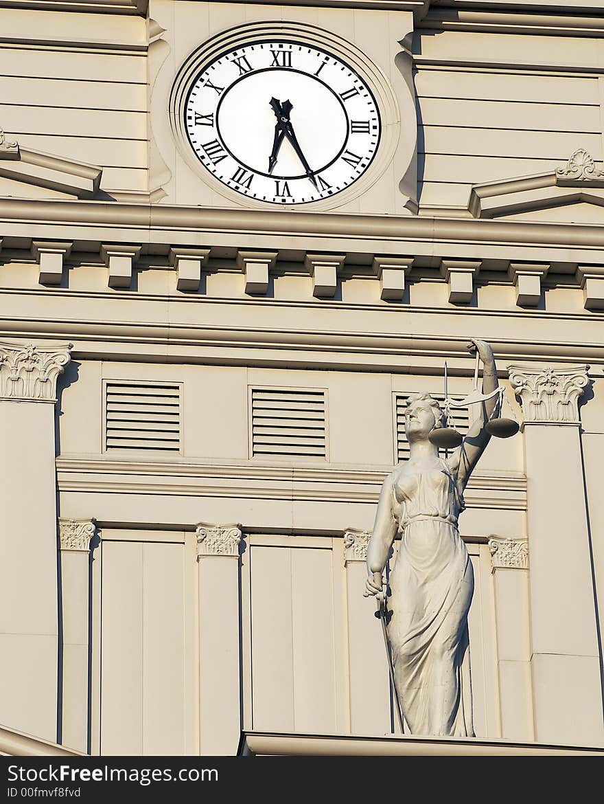 A clock and a woman statue at clock tower