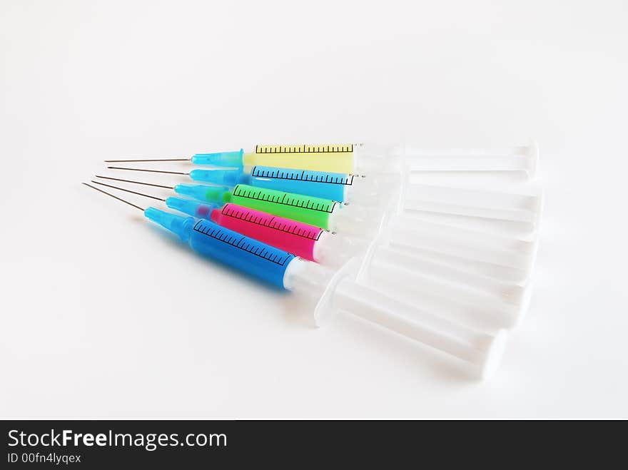 Glaring colored syringe lying one after another on a white background