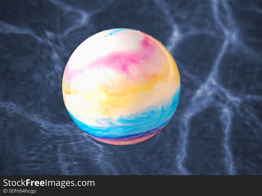 A colorful toy ball floating in a swimming pool. A colorful toy ball floating in a swimming pool