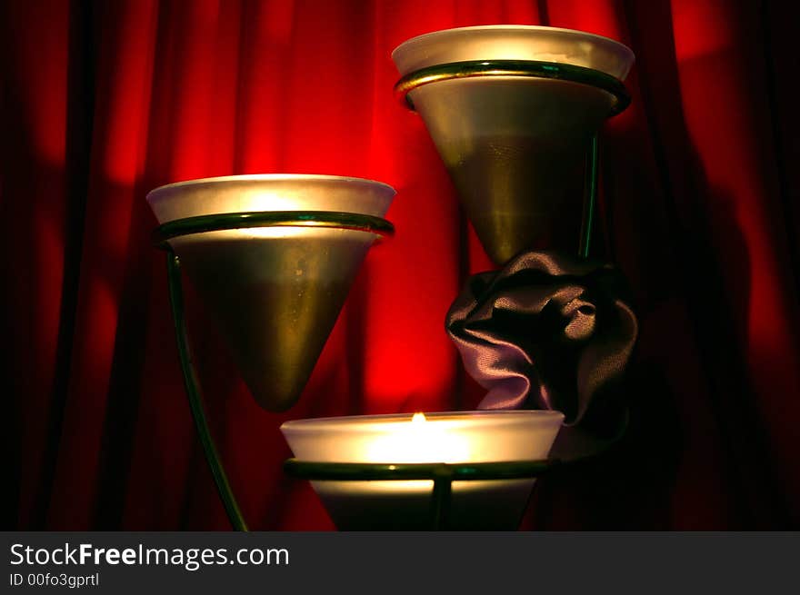 A tower of 3 candles glowing with a silken rose. A tower of 3 candles glowing with a silken rose.