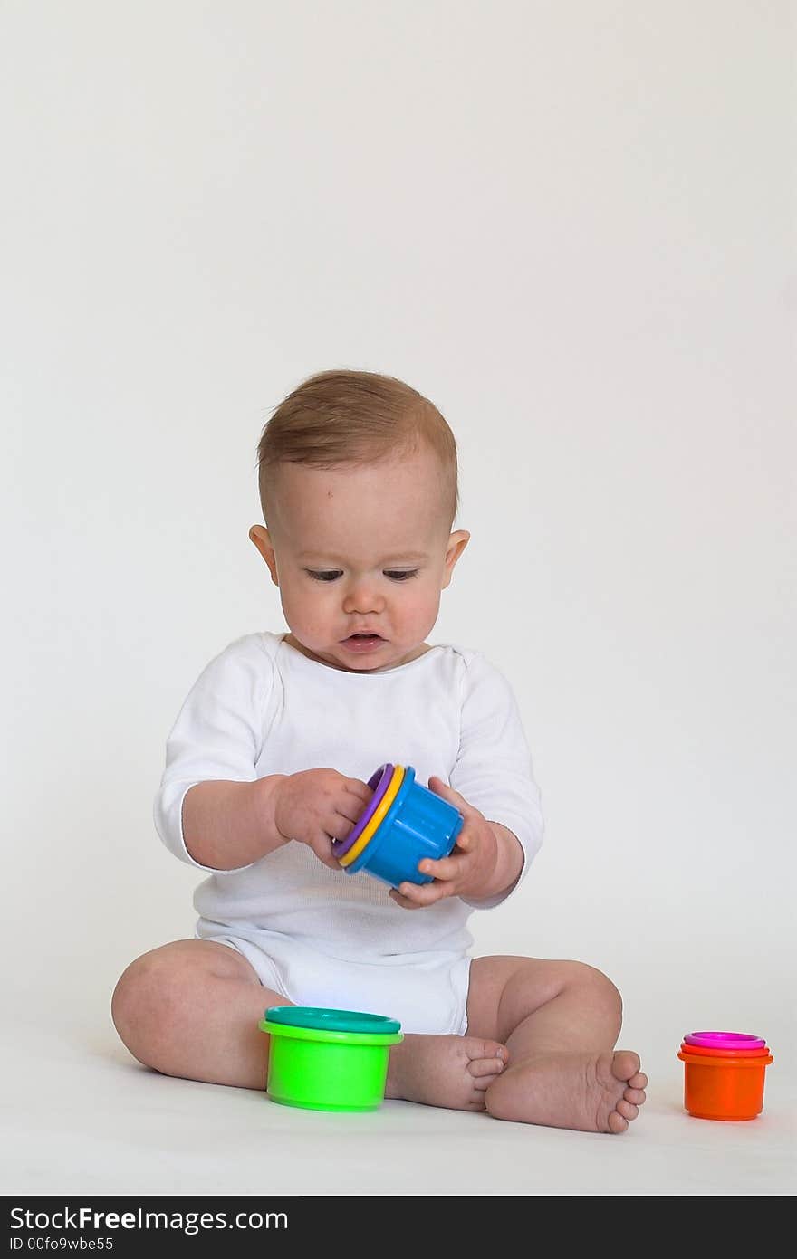 Image of an adorable baby playing with colorful stacking cups. Image of an adorable baby playing with colorful stacking cups