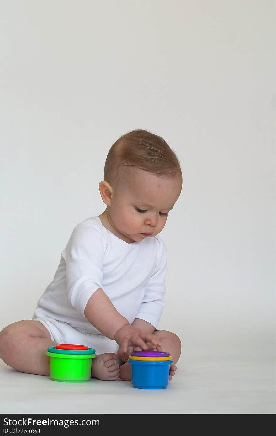 Image of an adorable baby playing with colorful stacking cups. Image of an adorable baby playing with colorful stacking cups