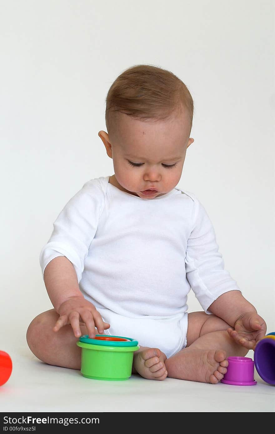 Image of an adorable baby playing with colorful stacking cups. Image of an adorable baby playing with colorful stacking cups