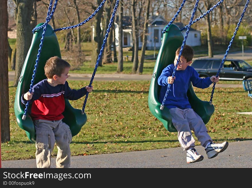 Boys Swinging at the playground having a great time