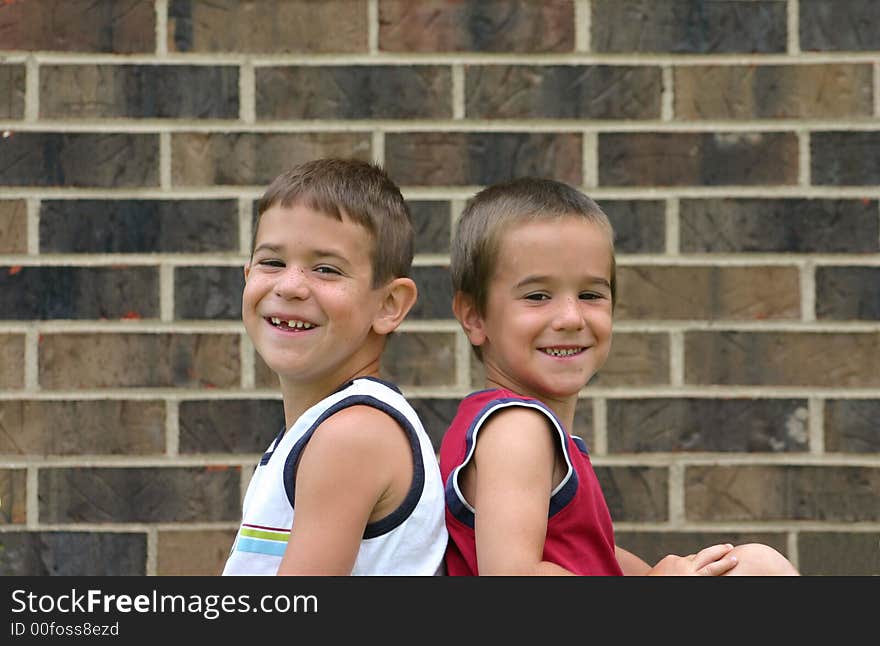 Two Brothers Smiling Against a Brick Wall