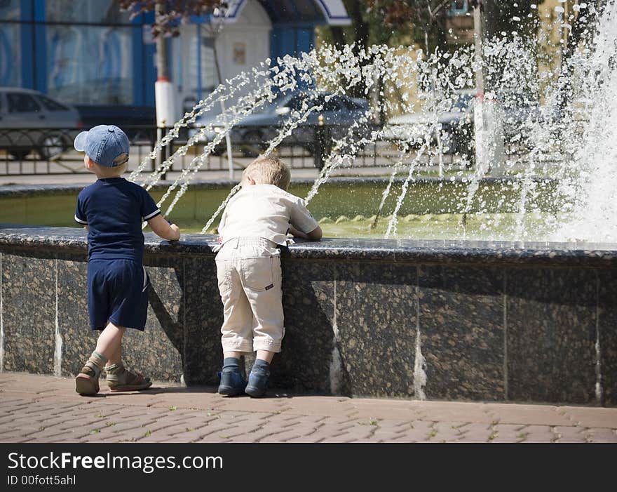 Two boys are watching water sprays at a fountain. Two boys are watching water sprays at a fountain