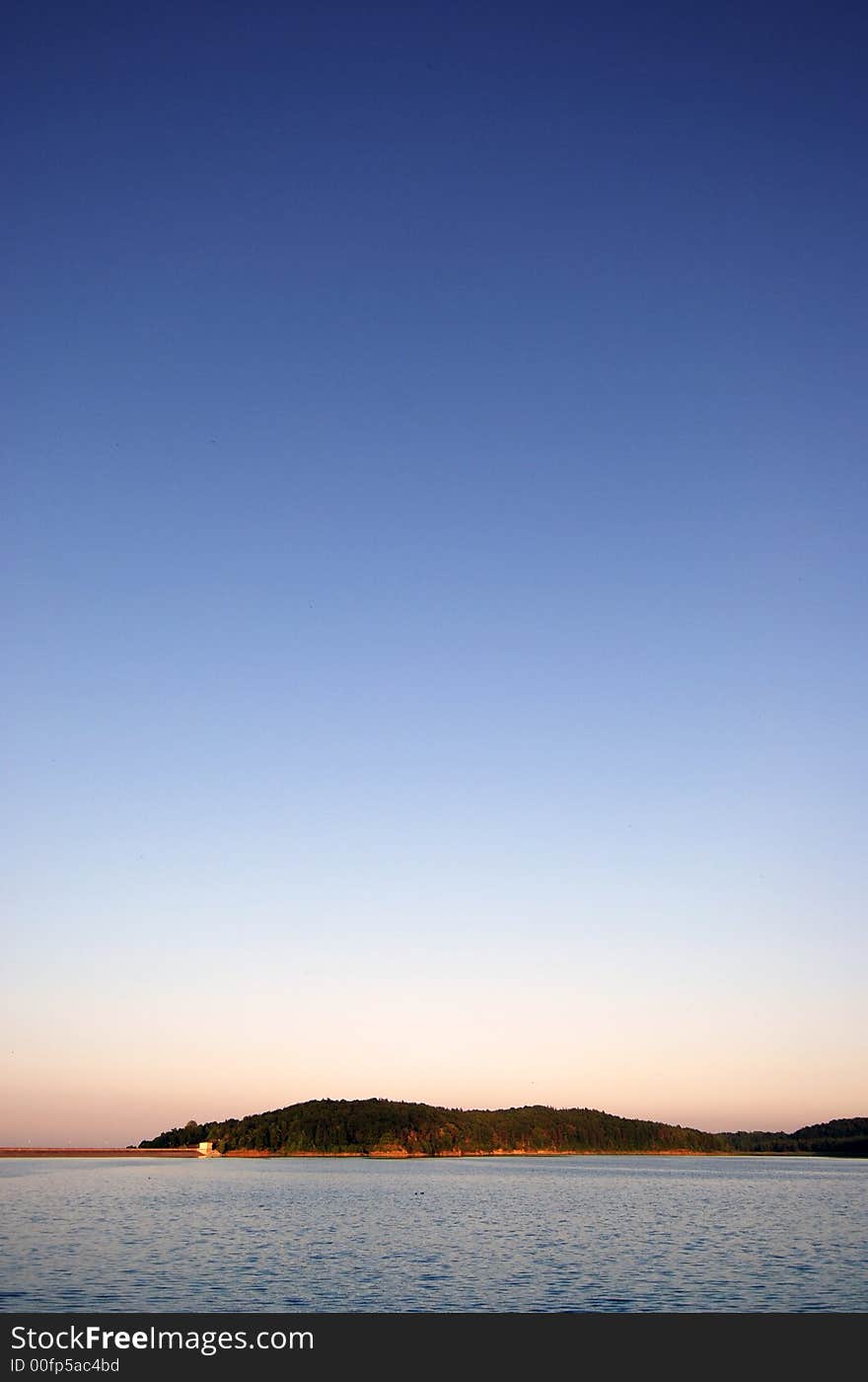 wavy lake on the landscape with green hills on the lakeside in the sunset. wavy lake on the landscape with green hills on the lakeside in the sunset