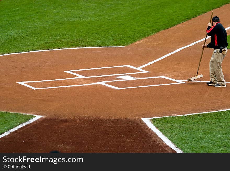 A groundskeeper preparing the home plate area before a baseball game. A groundskeeper preparing the home plate area before a baseball game.