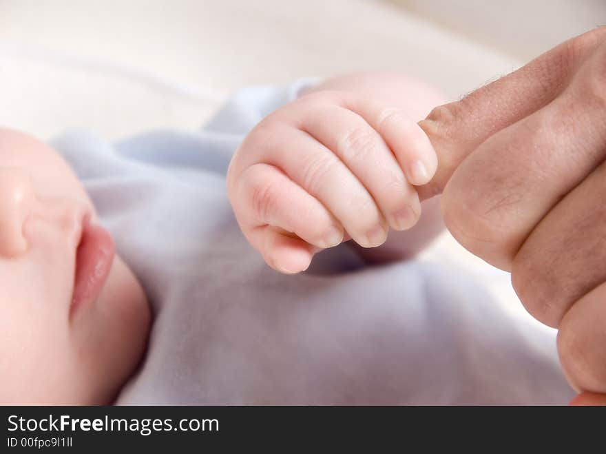 Small baby hand holding on to dad's finger