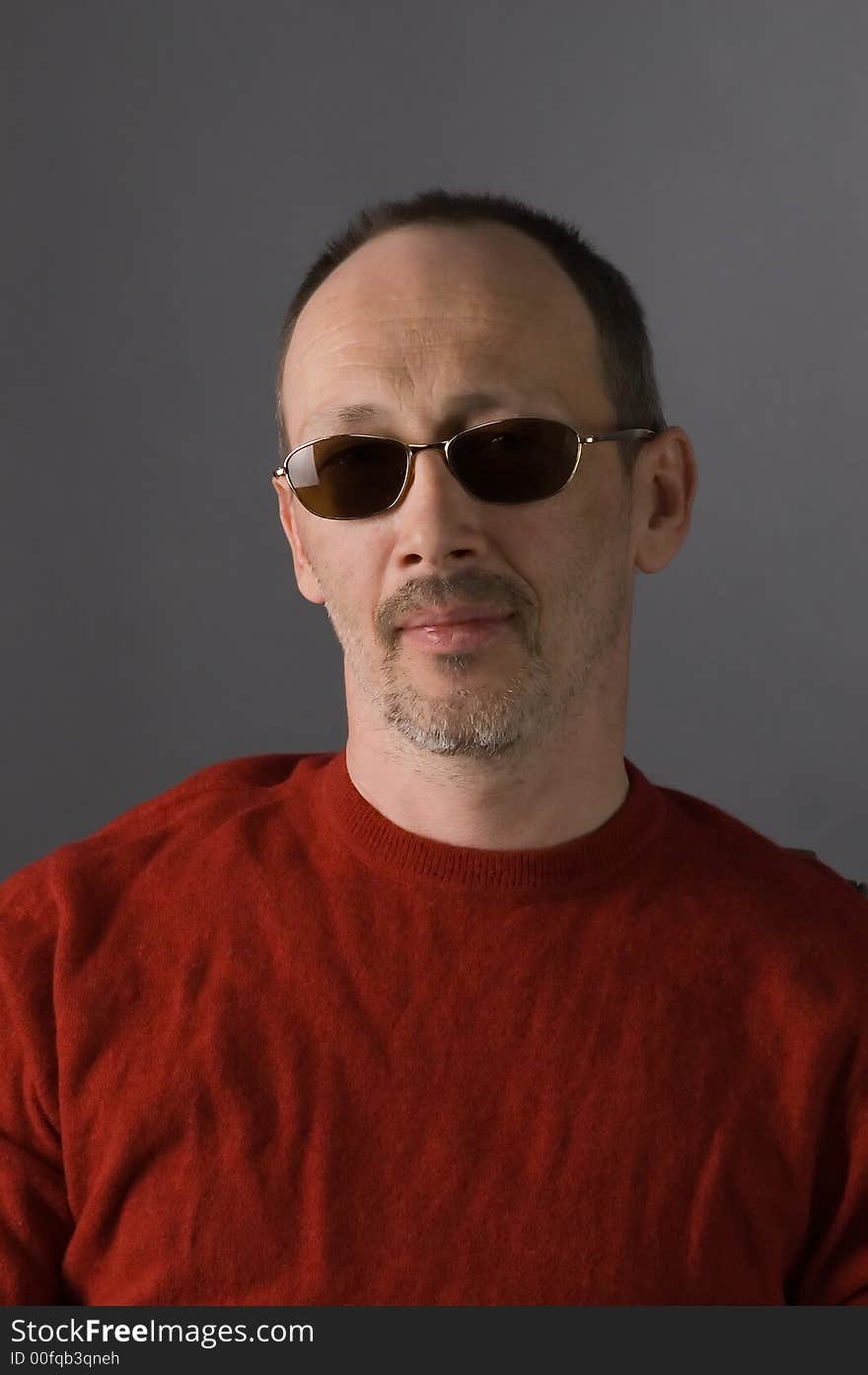 The man in a red sweater and glasses sits on a chair. The man in a red sweater and glasses sits on a chair