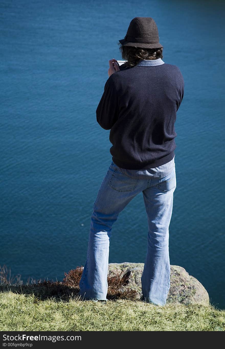 Young man videotapes his view of the ocean. Young man videotapes his view of the ocean