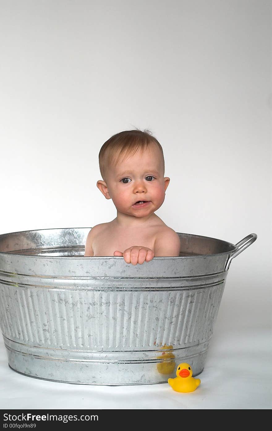 Image of cute baby sitting in a galvanized tub, with a rubber duck next to it. Image of cute baby sitting in a galvanized tub, with a rubber duck next to it