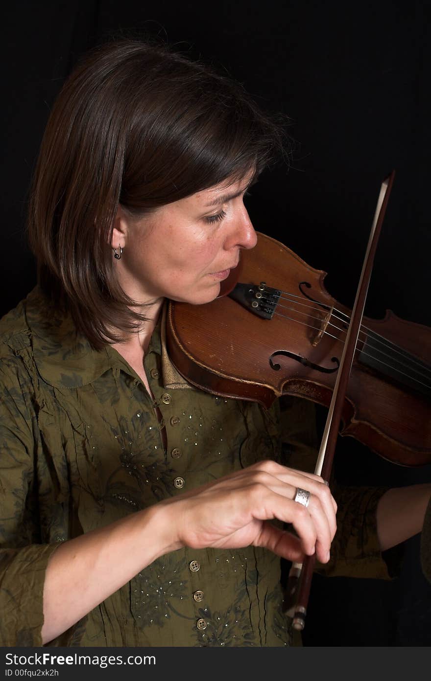 Mid-age woman playing violon over black background