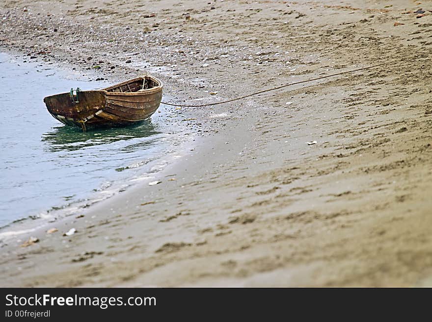 solitary wooden row boat beached in a small cove. solitary wooden row boat beached in a small cove