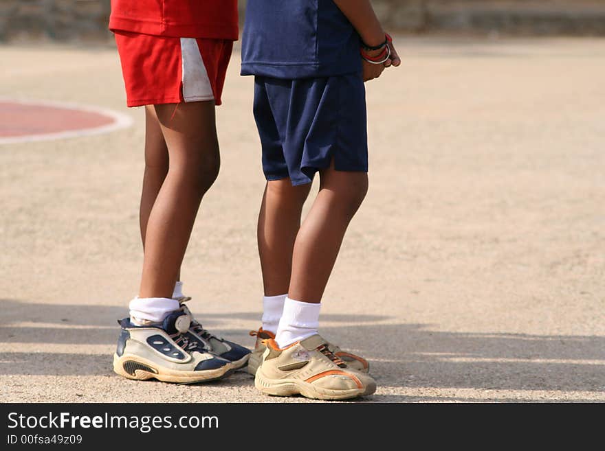 Two boys waiting their turn to play sport. A side shot of their lower bodies. Two boys waiting their turn to play sport. A side shot of their lower bodies