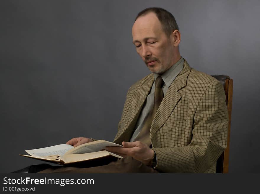 The man in a checkered suit reads the book. The man in a checkered suit reads the book