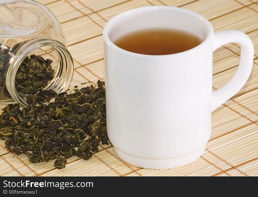 Cup of tea and tea leaves on bamboo background