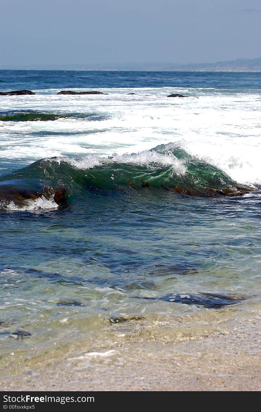 Wave on a sandy beach with a blue sky background