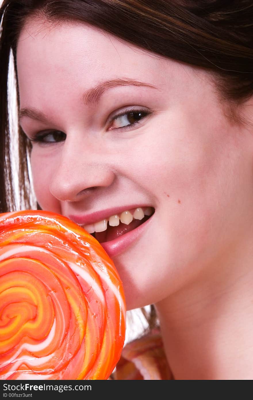 Attractive teen eating a giant lollipop.  Isolated on white.