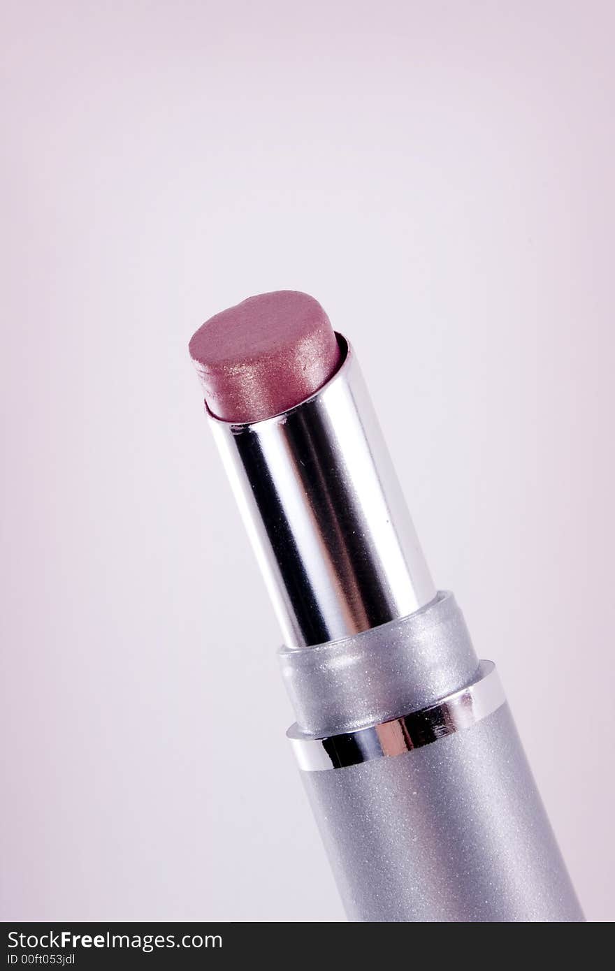 A tube of pink lipstick against a slightly pink vignetted background.