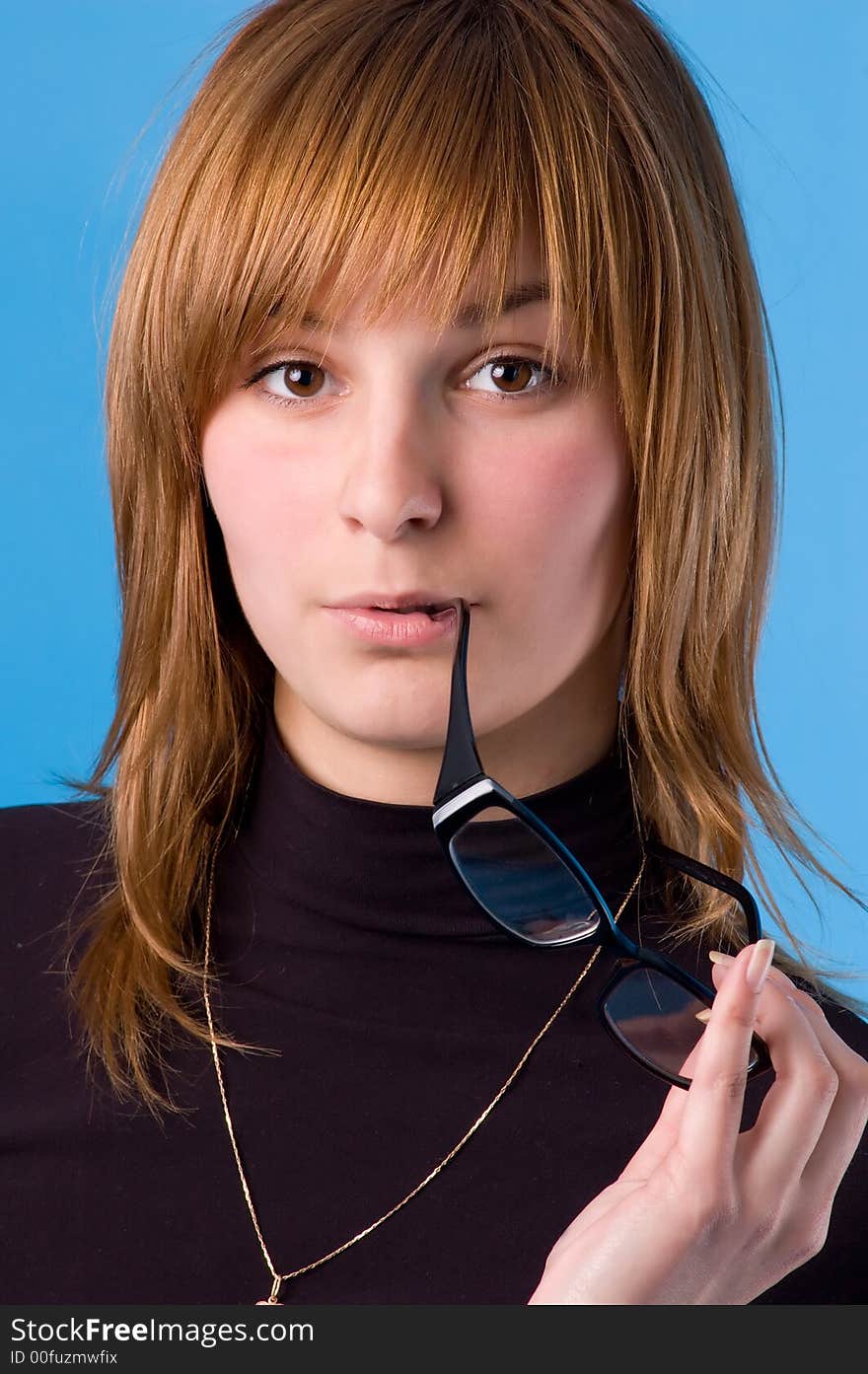 The girl on a blue background tries on glasses. The girl on a blue background tries on glasses