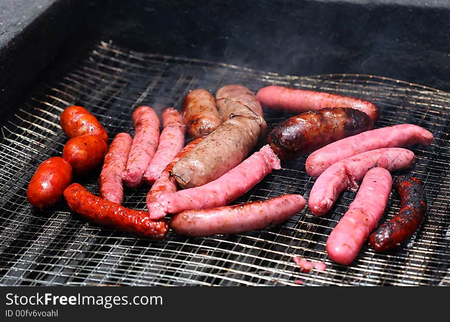 Cooking white and red sausage on outdoor barbecue