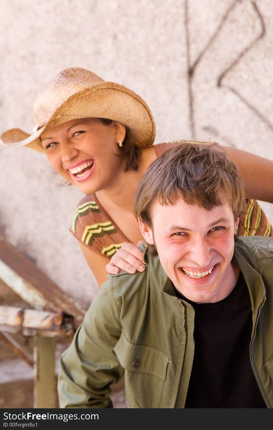 Cheerful pretty young couple on grunge wall background. Cheerful pretty young couple on grunge wall background