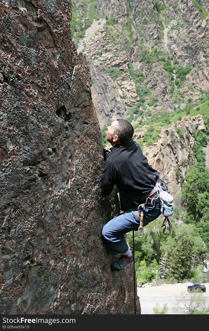 A rock climbing man climbs the edge of an arete. A rock climbing man climbs the edge of an arete