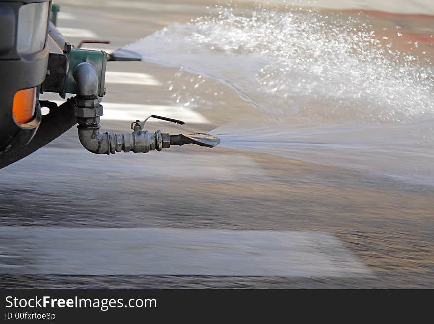 Panning and close-up image of a steam cleaning car in action in a city street.Complex motion blur effect produced by the water steam movement and the pavement movement below the water.The front car detail is in very good focus for a subject in motion. Panning and close-up image of a steam cleaning car in action in a city street.Complex motion blur effect produced by the water steam movement and the pavement movement below the water.The front car detail is in very good focus for a subject in motion.