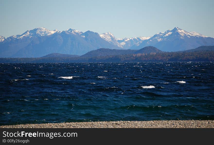 Snowcovered mountains on the shore of a lake in the background, lake in the foreground. Snowcovered mountains on the shore of a lake in the background, lake in the foreground.