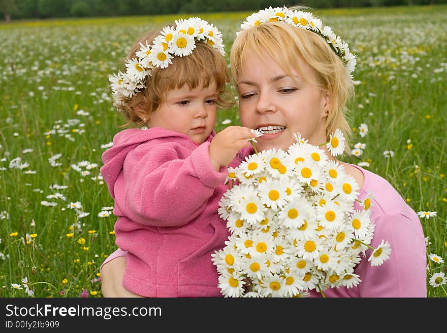 Woman and her baby girl looking at a beautiful daisy bouquet they just picked from the meadow. Woman and her baby girl looking at a beautiful daisy bouquet they just picked from the meadow