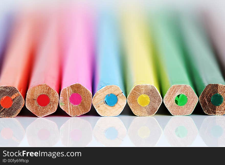 A row of color pencil ends with reflection. Shallow DOF with only ends sharp.