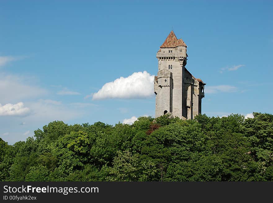 Castle with high tower above green forrest with blue sky with white cloudes. Castle with high tower above green forrest with blue sky with white cloudes