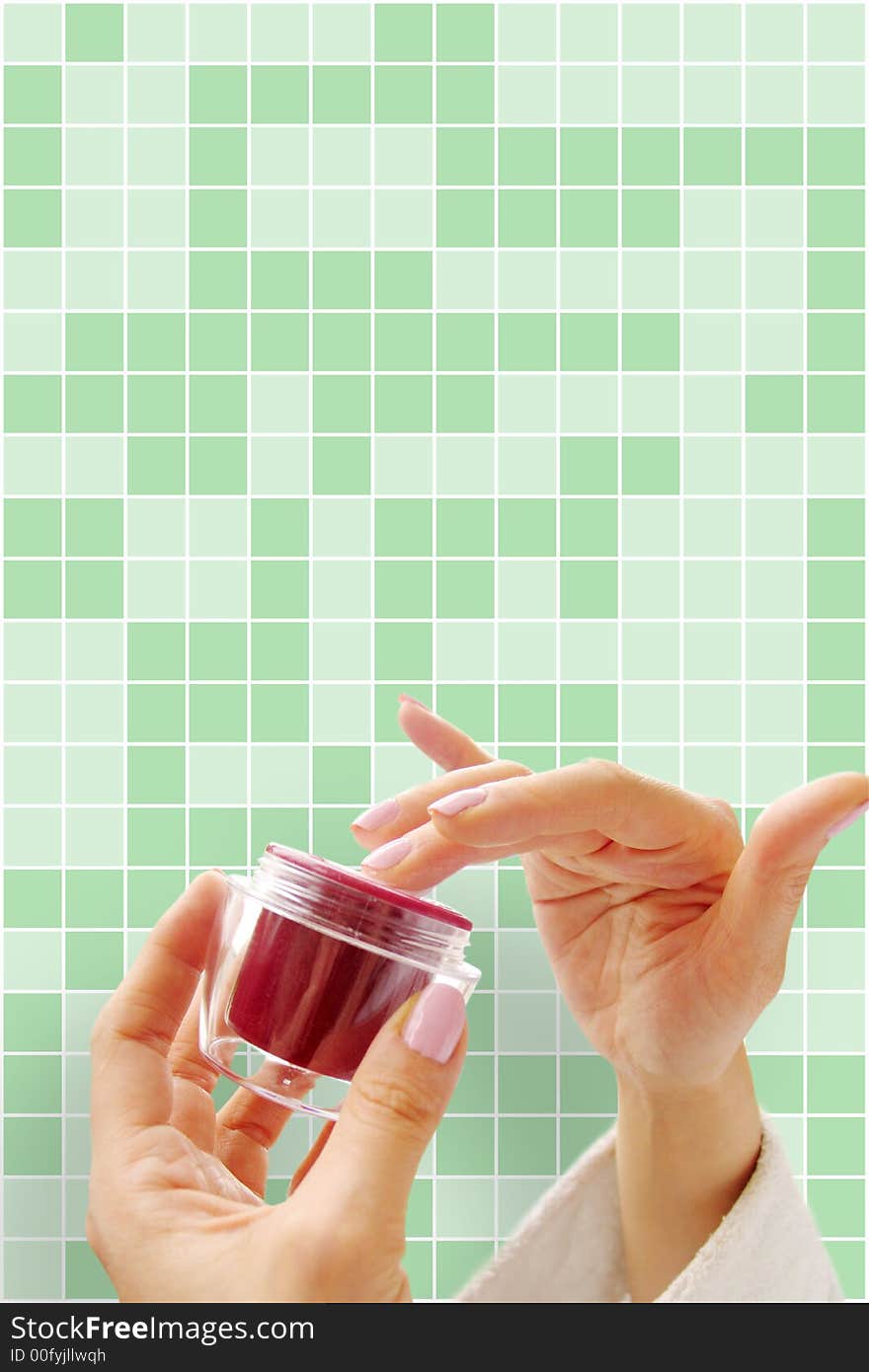 Female hands with a cosmetic cream on the green background