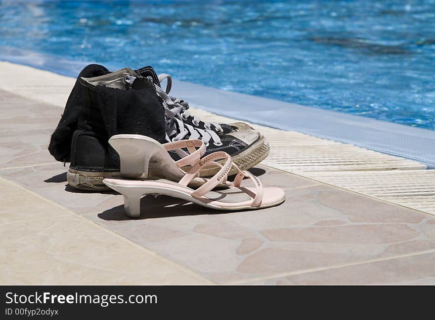 Two pairs of old shoes on edge of a pool. Two pairs of old shoes on edge of a pool